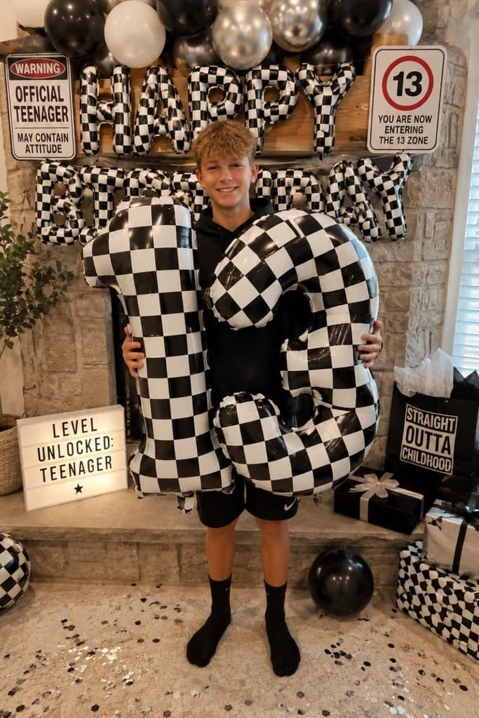 13 year old boy at a black and white checkered 13th birthday party with Official Teenager, Entering the 13 Zone, and Level Unlocked decorations.